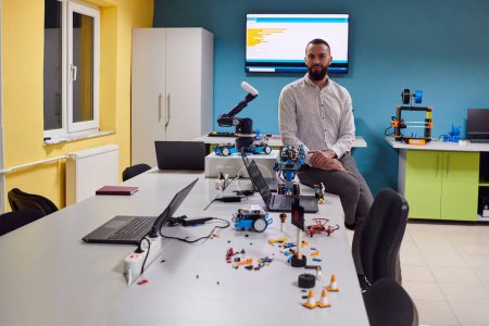 Photo for A bearded man in a modern robotics laboratory, immersed in research and surrounded by advanced technology and equipment - Royalty Free Image