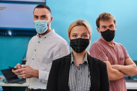 Photo for A group of colleagues stand ingin a robotics laboratory, arms crossed, wearing protective masks, symbolizing their teamwork and commitment to technological innovation and scientific research - Royalty Free Image
