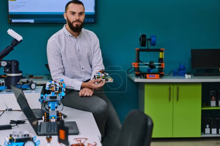 Photo for A bearded man in a modern robotics laboratory, immersed in research and surrounded by advanced technology and equipment - Royalty Free Image
