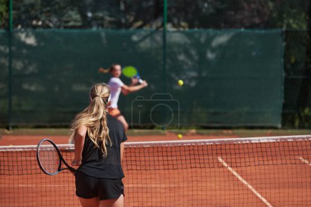 Téléchargez les photos : Jeunes filles dans un match de tennis animé par une journée ensoleillée, démontrant leurs compétences et leur enthousiasme sur un court de tennis moderne - en image libre de droit
