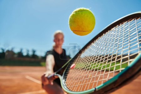 Photo for Close up photo of a young girl showing professional tennis skills in a competitive match on a sunny day, surrounded by the modern aesthetics of a tennis court - Royalty Free Image