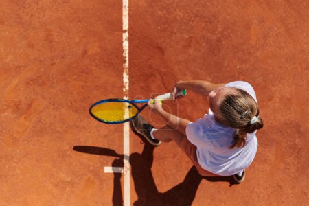 Téléchargez les photos : Vue de dessus d'une joueuse de tennis professionnelle sert la balle de tennis sur le terrain avec précision et puissance. - en image libre de droit