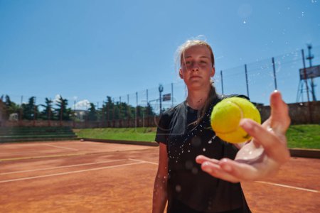 Téléchargez les photos : Avant son entraînement, la joueuse de tennis joue joyeusement avec une balle de tennis, rayonnant d'enthousiasme et de jeu, alors qu'elle se prépare mentalement et physiquement aux défis à venir sur la - en image libre de droit