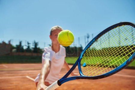 Close up photo of a young girl showing professional tennis skills in a competitive match on a sunny day, surrounded by the modern aesthetics of a tennis court