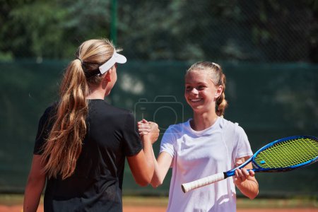 Téléchargez les photos : Deux joueuses de tennis serrant la main avec des sourires par une journée ensoleillée, respirant l'esprit sportif et l'amitié après un match compétitif - en image libre de droit