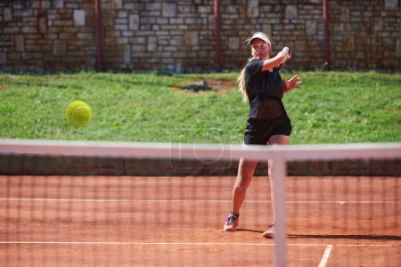 Foto de Una joven que muestra habilidades profesionales de tenis en un partido competitivo en un día soleado, rodeada por la estética moderna de una cancha de tenis - Imagen libre de derechos