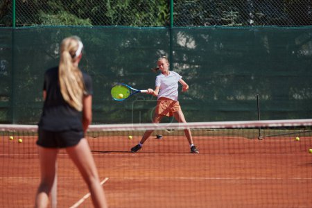 Photo for Young girls in a lively tennis match on a sunny day, demonstrating their skills and enthusiasm on a modern tennis court - Royalty Free Image