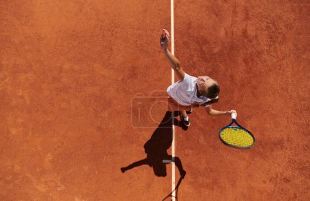 Photo for Top view of a professional female tennis player serves the tennis ball on the court with precision and power. - Royalty Free Image