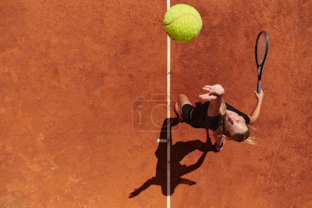 Photo for Top view of a professional female tennis player serves the tennis ball on the court with precision and power. - Royalty Free Image