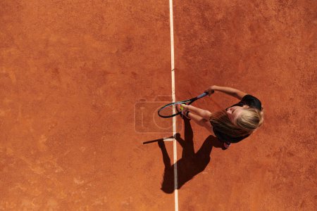 Téléchargez les photos : Vue de dessus d'une joueuse de tennis professionnelle sert la balle de tennis sur le terrain avec précision et puissance. - en image libre de droit