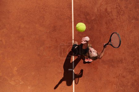 Vista superior de un jugador de tenis profesional sirve la pelota de tenis en la cancha con precisión y poder. 