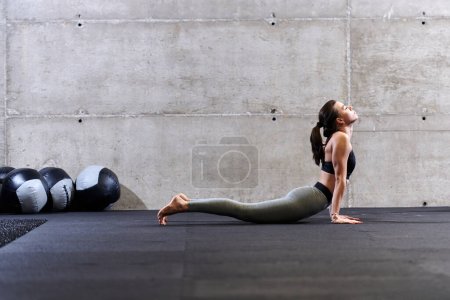 Foto de Fit mujer en un moderno gimnasio de trabajo flexibilidad y fuerza a través de varios ejercicios, lo que demuestra su compromiso con la aptitud. - Imagen libre de derechos