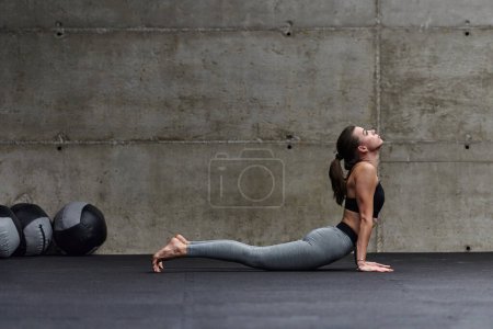 Foto de Fit mujer en un moderno gimnasio de trabajo flexibilidad y fuerza a través de varios ejercicios, lo que demuestra su compromiso con la aptitud. - Imagen libre de derechos
