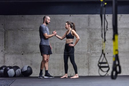 Foto de Hombre musculoso y mujer en forma en una conversación antes de comenzar su sesión de entrenamiento en un gimnasio moderno - Imagen libre de derechos