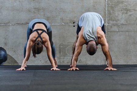 Téléchargez les photos : Un couple attrayant dans la salle de gym s'engageant dans divers exercices d'étirement ensemble, montrant leur dévouement à la forme physique, la flexibilité et le bien-être général. Avec des mouvements synchronisés, ils - en image libre de droit