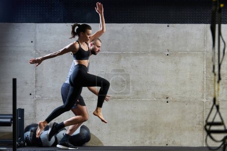 Foto de Una pareja en forma ejercitando varios tipos de saltos en un gimnasio moderno, demostrando su condición física, fuerza y rendimiento atlético. - Imagen libre de derechos
