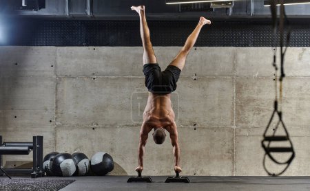 Ein muskulöser Mann in Handstandposition, der sein außergewöhnliches Gleichgewicht und seine Körperbeherrschung demonstriert, während er eine Vielzahl von Übungen durchführt, um seine allgemeine Körperstabilität und Stärke in einem modernen Fitnessstudio zu verbessern..