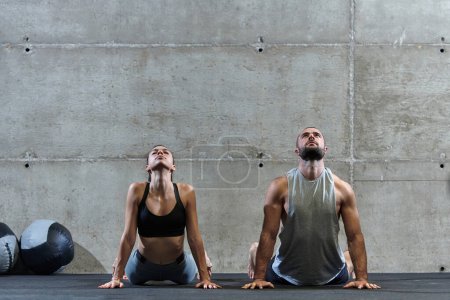 Photo for An attractive couple in the gym engaging in various stretching exercises together, showcasing their dedication to fitness, flexibility, and overall wellbeing. With synchronized movements, they - Royalty Free Image