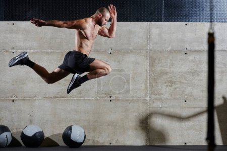 Un homme musclé capturé dans l'air alors qu'il saute dans un gymnase moderne, montrant son athlétisme, sa puissance et sa détermination à travers une routine de fitness de haute intensité.