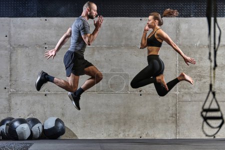Foto de Una pareja en forma ejercitando varios tipos de saltos en un gimnasio moderno, demostrando su condición física, fuerza y rendimiento atlético. - Imagen libre de derechos