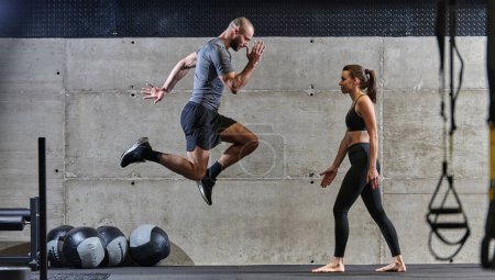 Una pareja en forma ejercitando varios tipos de saltos en un gimnasio moderno, demostrando su condición física, fuerza y rendimiento atlético.