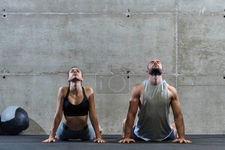 Photo for An attractive couple in the gym engaging in various stretching exercises together, showcasing their dedication to fitness, flexibility, and overall wellbeing. With synchronized movements, they - Royalty Free Image
