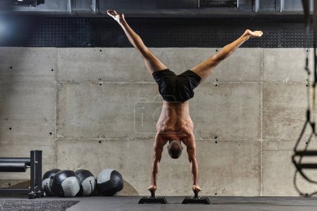 Photo for A muscular man in a handstand position, showcasing his exceptional balance and body control while performing a variety of exercises to enhance his overall body stability and strength in a modern gym. - Royalty Free Image