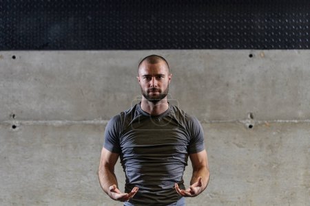 Un hombre musculoso que trabaja ejercicios de estiramiento para sus brazos y músculos corporales en el gimnasio moderno .