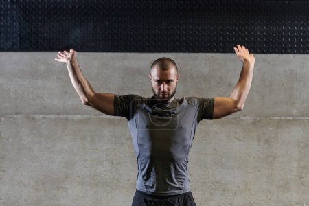 Foto de Un hombre musculoso que trabaja ejercicios de estiramiento para sus brazos y músculos corporales en el gimnasio moderno . - Imagen libre de derechos