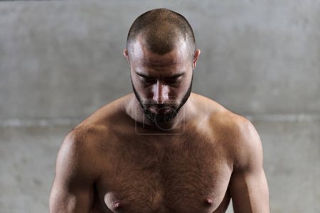 Téléchargez les photos : Un homme musclé pose dans la salle de gym, montrant sa force et son dévouement à la forme physique à travers un physique impressionnant et la transpiration scintillante sur son visage - en image libre de droit