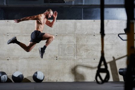 Un hombre musculoso capturado en el aire mientras salta en un gimnasio moderno, mostrando su atletismo, poder y determinación a través de una rutina de fitness de alta intensidad.