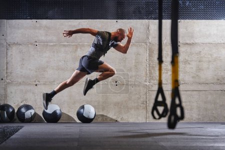 Photo for A muscular man captured in air as he jumps in a modern gym, showcasing his athleticism, power, and determination through a highintensity fitness routine. - Royalty Free Image