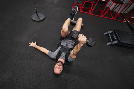 Foto de Un hombre musculoso se centra en hacer ejercicio con pesas en un gimnasio moderno, mostrando su determinación y compromiso con su régimen de fitness - Imagen libre de derechos