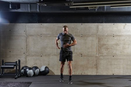 Foto de Un hombre musculoso que trabaja ejercicios de estiramiento para sus brazos y músculos corporales en el gimnasio moderno . - Imagen libre de derechos