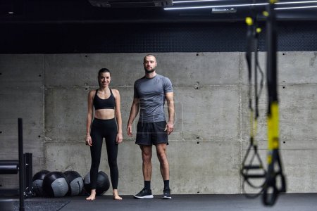 Photo for Muscular man and fit woman in a conversation before commencing their training session in a modern gym - Royalty Free Image