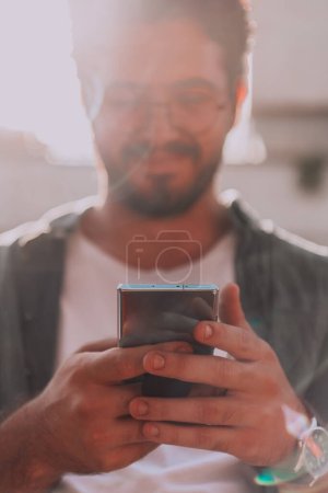 Téléchargez les photos : Un jeune homme utilise son smartphone à l'extérieur, mettant en valeur l'intégration transparente de la technologie et de la mobilité dans la vie professionnelle moderne - en image libre de droit