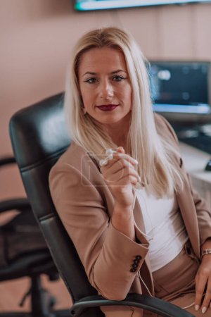 Photo for A businesswoman sitting in a programmers office surrounded by computers, showing her expertise and dedication to technology - Royalty Free Image