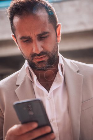 Foto de Un hombre de negocios que utiliza su teléfono inteligente al aire libre, mostrando la integración perfecta de la tecnología y la movilidad en la vida profesional moderna - Imagen libre de derechos
