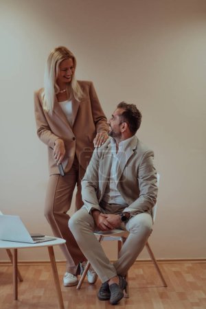 Téléchargez les photos : Un couple d'affaires pose pour une photographie ensemble dans un contexte beige, capturant leur partenariat professionnel et créant une image intemporelle d'unité et de succès - en image libre de droit