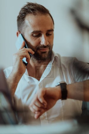 Foto de Un hombre de negocios hablando en su teléfono inteligente mientras está sentado en una oficina, mostrando su comportamiento profesional y comunicación activa - Imagen libre de derechos