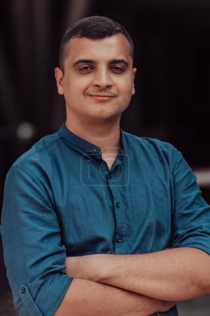 Foto de Un joven empresario exitoso con una camisa, con los brazos cruzados, posa al aire libre, con expresión confiada en su rostro - Imagen libre de derechos