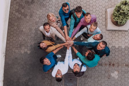 Foto de Foto vista superior de un grupo de empresarios y colegas tomados de la mano, mirando hacia la cámara, simbolizando la unidad y el trabajo en equipo - Imagen libre de derechos