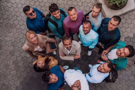 Téléchargez les photos : Une photo de vue de dessus du groupe d'hommes d'affaires et de collègues debout ensemble, regardant vers la caméra, symbolisant l'unité et le travail d'équipe - en image libre de droit