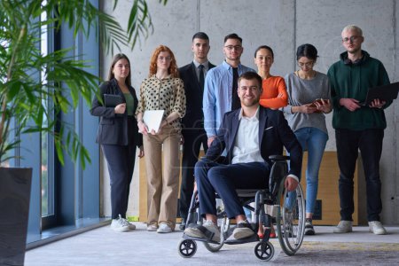 Photo for Diverse group of business people, including a businessman in a wheelchair in a modern office. - Royalty Free Image