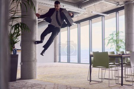 Photo for In the modern office, a businessman with a briefcase captivates everyone as he performs thrilling aerial acrobatics, defying gravity with his daring leaps and showcasing his agility with breathtaking - Royalty Free Image