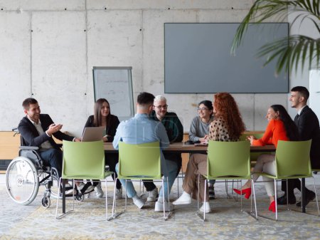 Un grupo diverso de profesionales de negocios, incluyendo una persona con discapacidad, se reunieron en una oficina moderna para una reunión productiva e inclusiva