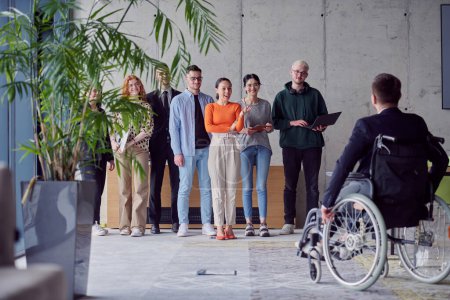 Photo for A group of diverse entrepreneurs gather in a modern office to discuss business ideas and strategies, while a colleague in a wheelchair joins them - Royalty Free Image