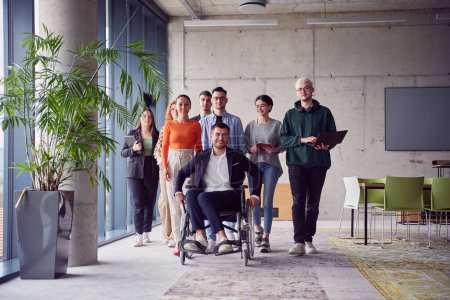 Photo for A diverse group of businessmen, including a businessman in wheelchair, confidently stride together through a modern, spacious office, epitomizing collaboration, inclusivity, and strength in unity. - Royalty Free Image