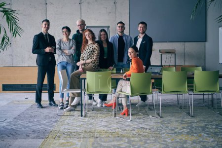 Téléchargez les photos : Un groupe diversifié de gens d'affaires prospères se rassemblent et posent pour une photo, mettant en valeur le travail d'équipe et l'autonomisation professionnelle dans un cadre de bureau moderne - en image libre de droit