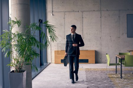 Photo for A confident businessman with a briefcase strides through a modern office, exuding charisma and determination, symbolizing success and professional excellence - Royalty Free Image